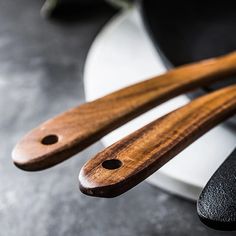 two wooden utensils sitting on top of a black and white plate next to each other