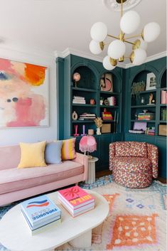 a living room filled with furniture and bookshelves next to a painting on the wall