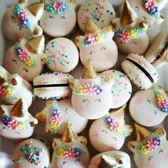 some white and gold decorated cookies with unicorn faces on them are in a plastic container