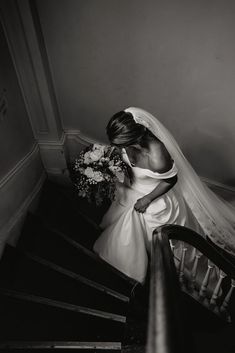 the bride is walking down the stairs with her bouquet