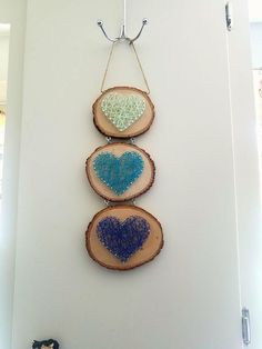 three pieces of wood are hanging on the wall with blue and green hearts painted on them