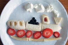 a white plate topped with fruit and banana slices on top of a boat shaped face