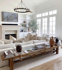 a living room filled with furniture and a fire place under a chandelier in front of a fireplace