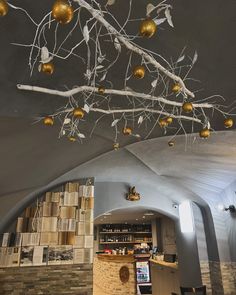 the ceiling is decorated with gold balls and branches hanging from it's rafters