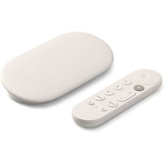 a white remote control sitting next to an oval shaped object on a white surface,