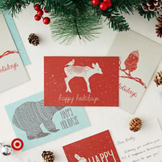 christmas cards and pine cones on a table with evergreen branches, pine cones, and other holiday greetings