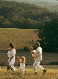 a group of people walking across a grass covered field