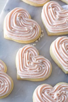 heart shaped cookies with pink icing on a cookie sheet