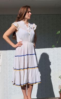 White Peasant Dress, Vintage 1970s gauze dress, prairie style 100% cotton, crinkle gauze   Elastic waistband with belt midi length skirt with blue and yellow decorative ribbons on the skirt part trimmed with yellow on the chest raised collar with ties, plastic beads on it. romantic frills at the shoulders unlined, bit sheer Fits size M Length: 45"  / 115 cm Shoulder to shoulder: 16.5" / 40-42 cm Bust:  16"-18.5" / 40 cm up to  47 cm Waist, flexible: 14.5"-19.5" / 36 cm , up to 50 cm Hips free Le White Peasant Dress With Ruffles, Yellow Peasant Dress, White Peasant Dress With Embroidered Border, White Peasant Dress, Romantic Cottagecore, 1970s Peasant Dress, White Ruffled Vintage Prairie Dress, 1970 Style, Gauze Dress