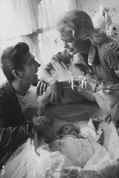 an old black and white photo of two women looking at a baby