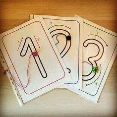 four cards with numbers on them sitting on top of a wooden table next to scissors and thread