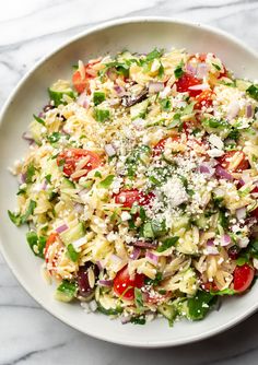 a white bowl filled with pasta salad and topped with parmesan cheese