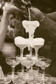 several wine glasses are stacked on top of each other and being filled with water from a faucet