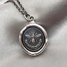 "BEE Wax Seal Necklace Pendant, Handmade Sterling Silver, Intaglio Seal Heirloom, Original Design Liliane Ting Studio Latin Motto \"vive ut vivas\" meaning \"Live as if you'll live forever.\". You will receive the piece which looks exactly as in the photo. >>Size: 23 * 21 mm excluding bail >>Material: Solid Sterling Silver >>Pendant Only Option: You may order \"Pendant Only\". This charm comes on a 5 mm sterling jump ring that you may thread onto your own necklace chain. >>Chain Options: The ste Silver Clay Pendant, Wax Seal Ring, Seal Necklace, Wax Seal Jewelry, Wax Seal Necklace, Bee Wax, Silver Metal Clay, Stamped Necklaces, Soldering Jewelry