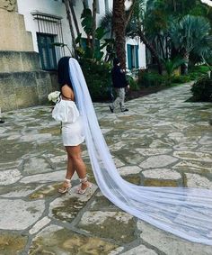 a woman is walking down the street with her veil blowing in the wind