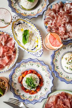 a table topped with plates filled with different types of meats and veggies