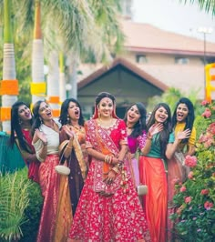 a group of women standing next to each other in front of some trees and flowers