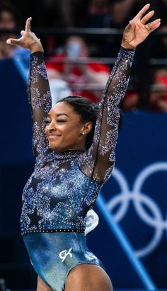 a woman in a blue leotard doing a trick on the balance beam at an olympics event