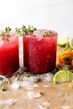 two glasses filled with red liquid and garnished with herbs