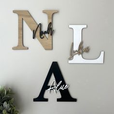 three wooden letters are hanging on the wall next to a potted plant and vase