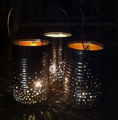 three metal buckets with lit candles in them