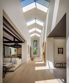 an open living room and dining area with skylights on the ceiling, hardwood flooring