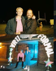 two men standing in front of a building at night and one man is holding his arm around the other