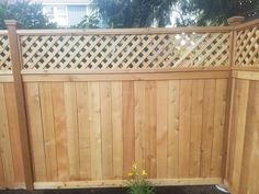 a wooden fence with lattice design in the top part and bottom part, next to a flower bed