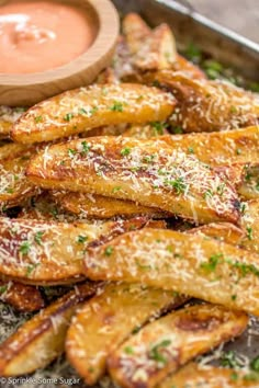 baked french fries with parmesan cheese on top and dipping sauce in the background