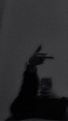 a blurry image of a person holding a cell phone in their hand and pointing to the sky