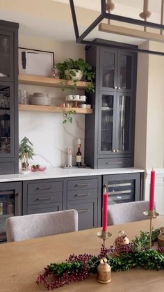 a dining room table with candles and christmas decorations on the top shelf in front of it