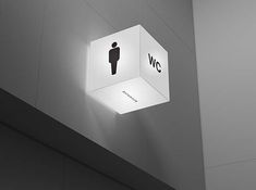 a bathroom sign hanging from the ceiling above a toilet paper dispenser in an office building