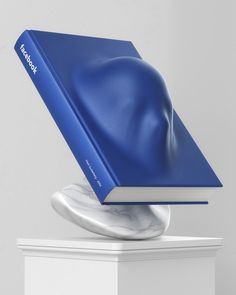 a blue book sitting on top of a white marble pedestal with a cover over it