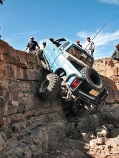 two men are climbing up the side of a rock wall with a truck on it