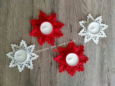 three red and white lace candle holders on a wooden table with two candles in the middle