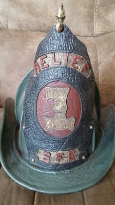 an old helmet with the word hell's on it sitting on a couch next to a pillow