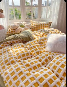 a bed with yellow and white comforter next to a window