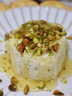 a white plate topped with a dessert covered in nuts and sauce on top of it