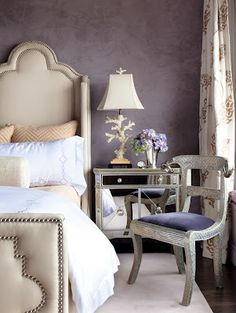 a bed room with a neatly made bed next to a table and chair in front of a window