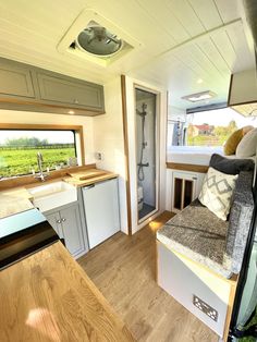 the kitchen and living area of an rv with wood flooring, windows, and sink