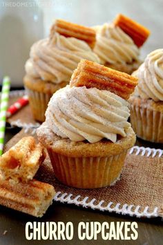 some cupcakes with icing and cinnamon sticks on a cloth next to them