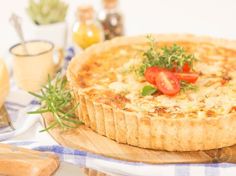 a quiche with tomatoes and herbs on a cutting board next to other food items