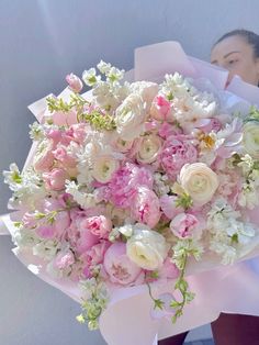 a woman holding a bouquet of pink and white flowers