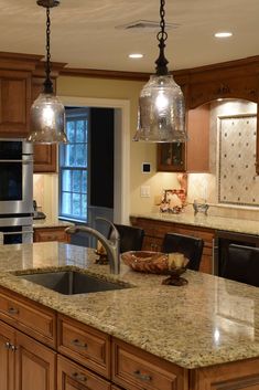 a kitchen with two lights hanging from the ceiling and an island in front of it