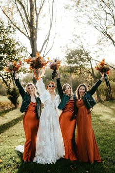 three women in dresses and jackets holding up their arms with sunflowers on them