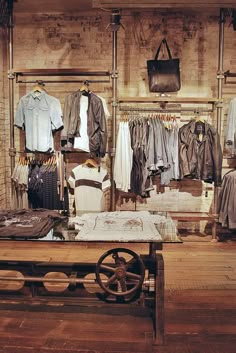 an old fashion store with clothes on racks and tables in front of the display window