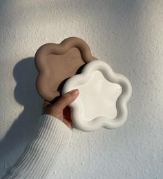 a hand holding a white and brown object in front of a white wall with snow on it