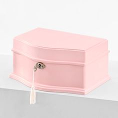 a pink jewelry box with a tassel hanging from it's lid and handle