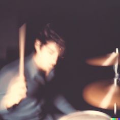 a blurry photo of a man playing drums in front of a drum set with his eyes closed