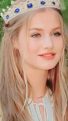 a young blonde girl wearing a tiara and smiling at the camera with blue eyes